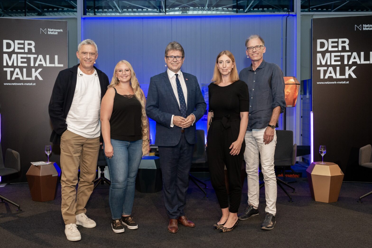 Fünf Personen stehen zusammen bei der Veranstaltung 'Der Metall Talk' in einem Innenraum.